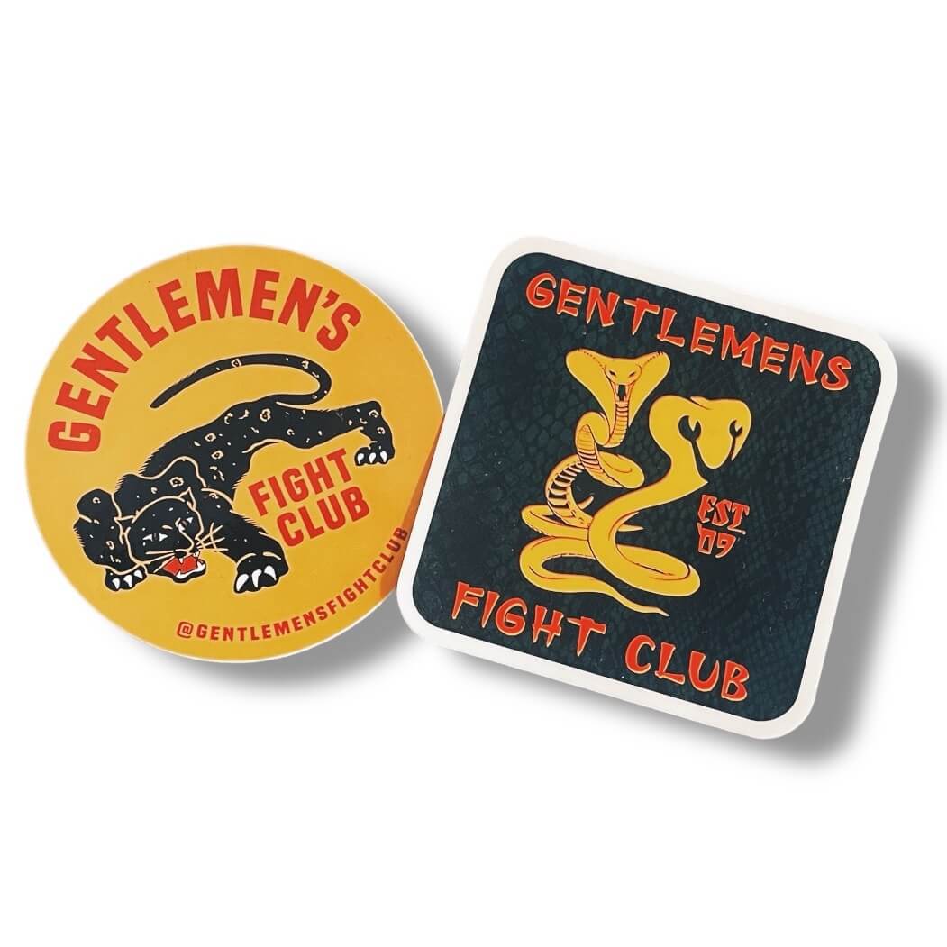 Two Stickers that read Gentlemen's Fight Club.  One is mustard yellow with a red font and black panther.  One is Black with a faint snakeskin texture in the background and red font that reads Gentlemen's Fight Club  Est. 09 and yellow snake